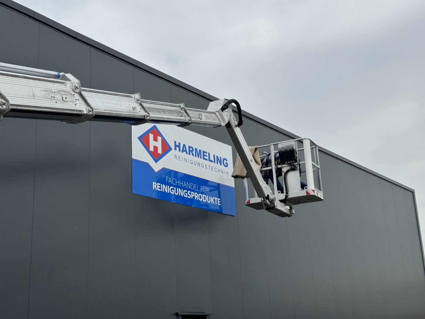 Montage eines Firmenschilds mit Hubsteiger